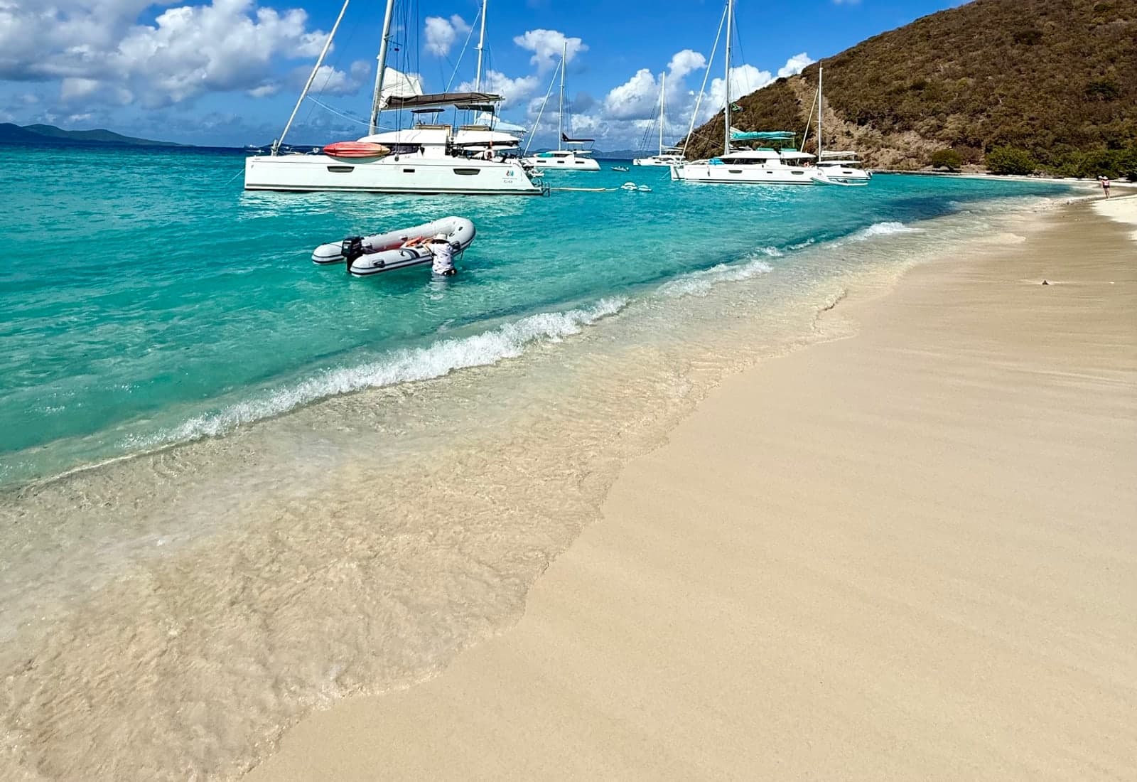 Sailboats anchored near a bright Caribbean beach