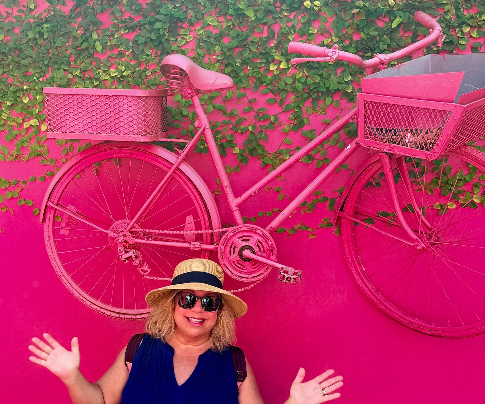 Andrea Sanders smiling in front of a bright pink bicycle mural